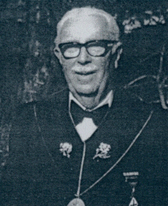Henry Emerson Henry Emerson; Past Supreme MAGI; An elderly man with white hair and glasses, dressed in a dark suit with a bow tie and pins or medals on his chest, stands outdoors and smiles at the camera.