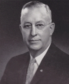 Laurence E. Eaton Laurence E. Eaton; Past Supreme MAGI; Black and white portrait of an older man wearing glasses, a suit, and a tie, facing the camera with a neutral expression against a dark background.